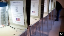 FILE - A lone voter fills out a ballot alongside a row of empty booths at a polling station in the Terrace Park Community Building on Election Day in Cincinnati, Ohio, Nov. 8, 2016.