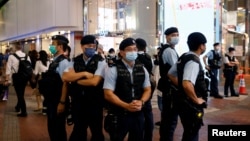 FILE - Police stand guard at the site where a man allegedly stabbed a policeman then stabbed himself in the chest with the knife and died on the anniversary of the city's return to Chinese rule, at Causeway Bay in Hong Kong, July 2, 2021. 