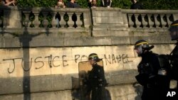 FILE - Polisi berpatroli melewati grafiti bertuliskan "Keadilan untuk Nahel" saat aksi protes para pemuda di alun-alun Concorde, Paris, Prancis, Jumat, 30 Juni 2023. (AP/Lewis Joly, File)