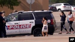 FILE - People raise their hands as they leave a shopping center after a shooting May 6, 2023, in Allen, Texas. 