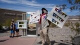 A demonstrator protests visitors to Death Valley National Park, July 16, 2023, in Death Valley National Park, Calif.