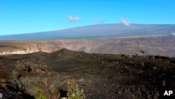 FILE - Hawaii's Mauna Loa volcano, background, towers over the summit crater of Kilauea volcano in Hawaii Volcanoes National Park on the Big Island on April 25, 2019.