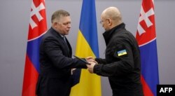 Denys Shmyhal (kanan) dan mitranya dari Slovakia Robert Fico bertukar folder dengan dokumen yang ditandatangani selama pertemuan mereka di Uzhhorod, 24 Januari 2024, di tengah invasi Rusia ke Ukraina. (HANDOUT / FACEBOOK / AFP)