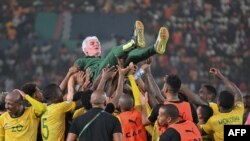 Técnico da África do Sul, Hugo Bross, atirado para cima pelos seus jogadores depois da conquista do terceiro lugar no CAN 2023, no Estádio Felix Houphouet-Boigny, em Abidjan, 10 fevereiro 2024 (FotoSia KAMBOU / AFP)