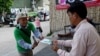 In this photo taken on July 4, 2023, a member (L) of Cambodia's Grassroots Democratic Party (GDP) distributes political campaign leaflets during the general election campaign in Phnom Penh.