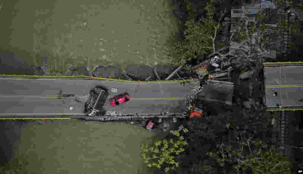 Mobil terlihat di atas dan di bawah jembatan El Alambrado yang runtuh sehari sebelumnya di Caicedonia, Kolombia.