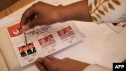Seorang pendukung calon presiden Anies Baswedan dan calon wakil presiden Muhaimin Iskandar berpose saat melakukan simulasi pemungutan suara dalam kampanye yang diselenggarakan oleh relawan pemuda di Jakarta pada 8 Februari 2024. (Foto: AFP)