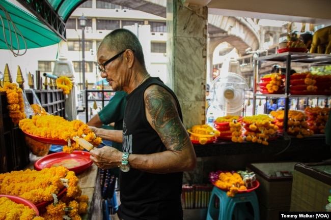 A worker at the Erawan Shrine in Bangkok cools down by standing by an electric fan and eating ice-pops in Bangkok, Thailand, April 23, 2023.