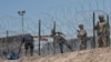 2023 年 5 月 11 日，移民穿过铁丝网屏障，从墨西哥华雷斯城进入德克萨斯州埃尔帕索。