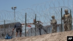 2023 年 5 月 11 日，移民穿過鐵絲網屏障，從墨西哥華雷斯城進入德克薩斯州埃爾帕索。