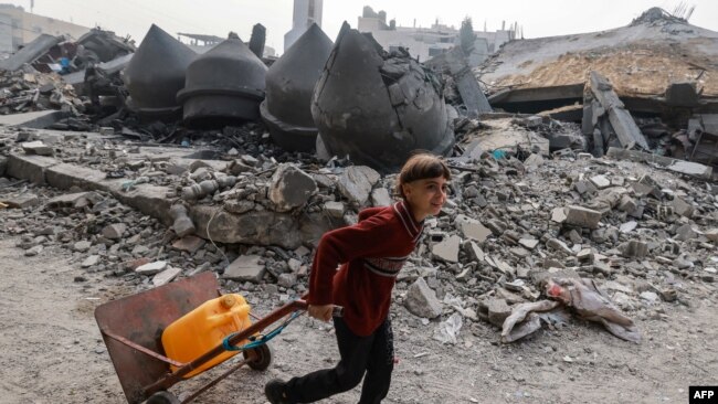 A child carries a jerrycan of water as he walks in front of the Al-Faruq mosque, leveled by Israeli bombardment in Rafah in the southern Gaza Strip on a foggy day, Feb. 25, 2024.