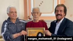 کریم محمدی (نفر وسط در تصویر) که تصویر فرزندش نرگس محمدی را در دست گرفته است