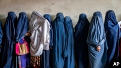 FILE - Afghan women wait to receive food rations distributed by a humanitarian aid group, in Kabul, Afghanistan, on May 23, 2023.