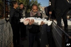 Seorang pria Palestina di sebuah rumah sakit di Rafah membopong jenazah cucunya yang tewas akibat pengeboman Israel di Gaza, Jumat, 22 Desember 2023. (Foto: Fatima Shbair/AP Photo)