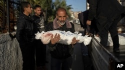 A Palestinian man carries the body of his grandson who was killed in the Israeli bombardment of the Gaza Strip, at the hospital Rafah, southern Gaza, Dec. 22, 2023.