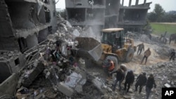 以色列周五对加沙地区代尔·巴拉赫城进行空袭。图为遭到轰炸的一处居民楼废墟。