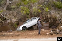 In this photo provided by the Libyan government, a car sits partly suspended in trees after being carried by floodwaters in Derna, Libya, on Monday, Sept. 11, 2023. (Libyan government handout via AP)