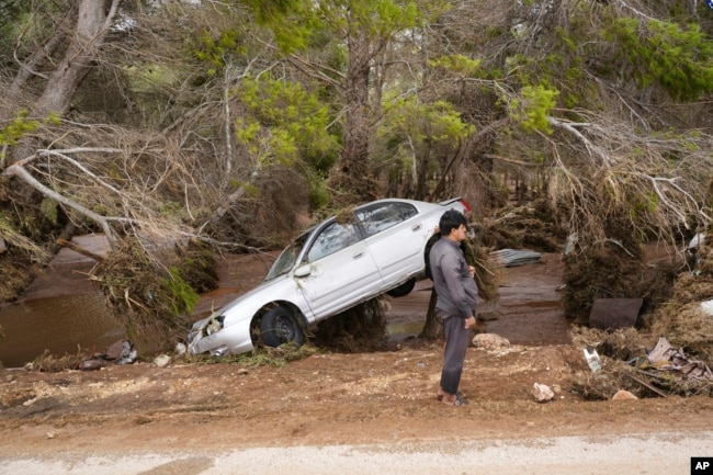 In this photo provided by the Libyan government, a car sits partly suspended in trees after being carried by floodwaters in Derna, Libya, on Monday, Sept. 11, 2023. (Libyan government handout via AP)