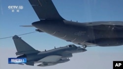 In this image taken from video footage run Saturday, April 8, 2023 by China's CCTV, a Chinese fighter jet performs an mid-air refueling maneuver at an unspecified location. 