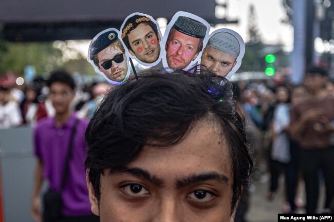 Penggemar band rock asal Inggris Coldplay mengenakan ikat kepala bergambar anggota band di pintu masuk Stadion Gelora Bung Karno jelang konser tur dunia di Jakarta pada 15 November 2023. (Foto: AFP/Mas Agung Wilis)