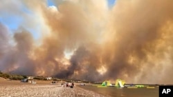 Clouds of smoke from a forest fire rise to the sky on the island of Rhodes, Greece, July 22, 2023. A large blaze burning on Rhodes forced the evacuation of two seaside resorts.
