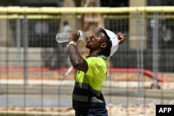 Seorang pekerja konstruksi terlihat sedang minum di tengah cuaca panas yang melanda Spanyol, Barcelona, 18 Juli 2023. (Foto: AFP)