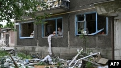 A woman looks out of a blown window of her flat in a damaged residential building following overnight Russian strike in the town of Selydove, Donetsk region, on June 14, 2024.