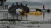 中国杭州第十九届亚运会期间，游客们穿过广受欢迎的西湖风景区金色公牛雕塑旁的石桥