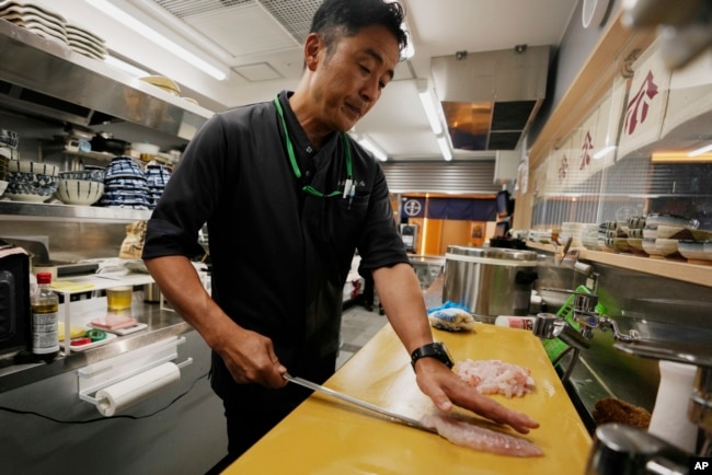 Katsumasa Okawa, owner of a fish store and a restaurant, cuts flounder meat as he prepares at his restaurant in Iwaki, northeastern Japan, July 13, 2023.