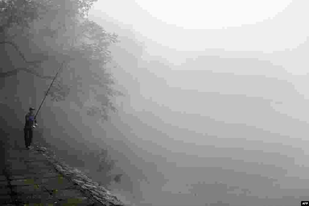 A man fishes at a lake on a foggy morning in Hanoi.