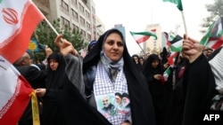 Para perempuan Iran melambaikan bendera nasional Iran dalam demo di luar gedung bekas Kedubes AS di Teheran sebagai dukungan terhadap warga Palestina di Jalur Gaza dan peringatan 44 tahun krisis sandera di Iran, Sabtu, 4 November 2023. (Foto: Atta Kenare/AFP)