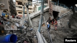 Warga Palestina berdiri di tengah puing-puing sekolah milik PBB yang menampung para pengungsi, menyusul serangan Israel, di tengah konflik Israel-Hamas, di Kota Gaza, 18 Juli 2024. (Foto: Dawoud Abu Alkas/Reuters)