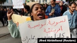 (FILE) A woman carries a banner during a protest in Tunisia.