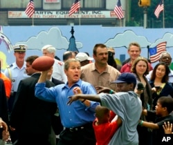 FILE - President George W. Bush celebrates the Fourth of July holiday in Philadelphia by playing street football with kids at a block party sponsored by the Greater Exodus Baptist Church to promote his faith-based initiative on July 4, 2001. (AP Photo/J. Scott Applewhite, File)