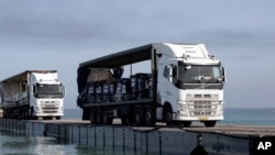 FILE - Gambar yang disediakan oleh Angkatan Darat AS ini menunjukkan truk bermuatan bantuan dari Uni Emirat Arab dan Badan Pembangunan Internasional Amerika Serikat melintasi Dermaga Trident sebelum tiba di pantai di Jalur Gaza, 17 Mei 2024.