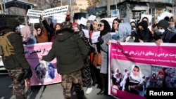 FILE - Members of the Taliban forces stop Afghan women during a rally to protest against what protesters say is Taliban restrictions on women, in Kabul, Afghanistan, December 28, 2021. 