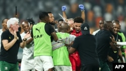 Williams, guarda-redes sul-africano, abraçado por colegas e técnico no final do jogo contra Cabo Verde, Estádio Charles Konon Banny, Yamoussoukro, Costa do Marfim, 3 fevereiro 2024