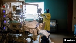 FILE - A nurse performs a wellness check of a patient a Humber River Hospital in Toronto, April 15, 2021. Canada unveiled an immigration initiative to attract tech workers to complement an earlier effort to attract health care and other skilled workers.