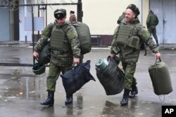 FILE - Recruits carry their new gear at a military recruitment center in Rostov-on-Don, Russia, Oct. 31, 2022.