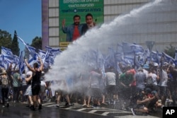 Israeli police use a water cannon to disperse demonstrators blocking a road during a protest against plans by Prime Minister Benjamin Netanyahu's new government to overhaul the judicial system, in Tel Aviv, July 11, 2023.