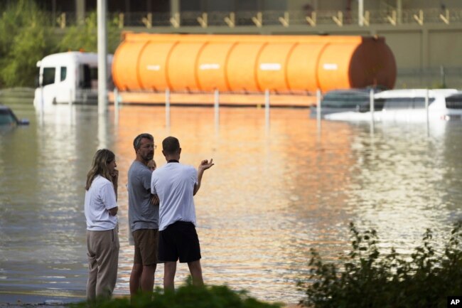 People look out at floodwater covering a major road in Dubai, United Arab Emirates, Wednesday, April 17, 2024. (AP Photo/Jon Gambrell)