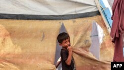 A boy stands outside a tent at a camp for people displaced by conflict in Khan Yunis in the southern Gaza Strip on July 11, 2024, amid the ongoing conflict in the Palestinian territory between Israel and Hamas.