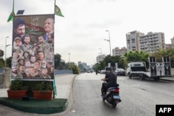 Seorang pengendara sepeda motor melewati poster yang menunjukkan anggota gerakan Syiah Amal, sekutu Hizbullah, di pinggiran selatan Beirut, 21 Juni 2024. (ANWAR AMRO / AFP)
