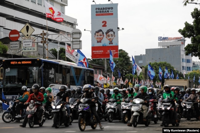 Masyarakat berjalan melewati baliho Menteri Pertahanan dan calon Presiden Prabowo Subianto dan pasangannya Gibran Rakabuming Raka di Jakarta, 12 Januari 2024. (Foto: REUTERS/Willy Kurniawan)