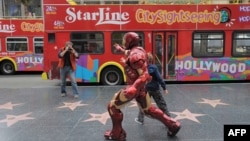 Seorang turis tengah memotret pria berkostum karakter film aksi di Hollywood Boulevard, Hollywood, California, 7 Maret 2013. (JOE KLAMAR / AFP)