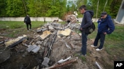 People look at fragments of a television tower which was broken in half after it was hit by a Russian missile in Kharkiv, Ukraine, April 22, 2024.