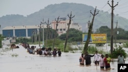 People, many carrying their belongings, wade through a flooded road after heavy rains in Vijayawada, India, Sept. 2, 2024. 