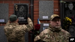 Kolega kači spomen sliku na grob ukrajinskog vojnika Oleksandra Hrijanika u Kijevu, Ukrajina, 28. oktobra 2023. Hrijanik je poginuo u borbi u maju 2022. u gradu Mariupolju, ali je kremiran tek nedavno nakon što su njegovi posmrtni ostaci pronađeni i identifikovani.