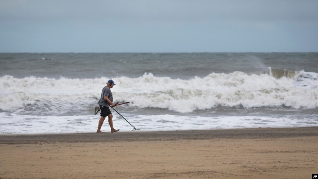 A man uses a metal detector on the Virginia Beach oceanfront during Tropical Storm Ophelia on Sept. 23, 2023, in Virginia Beach, Va.