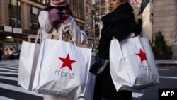 FILE - Sejumlah konsumen menenteng tas belanja Macy's saat hari belanja 'Black Friday" di New York, 24 November 2023. Ekonomi Amerika Serikat tumbuh lebih kuat dari proyeksi pada Kuartal-II 2024 ditopang konsumsi dalam negeri yang kuat. (Foto: Yuki Iwamura/AFP)